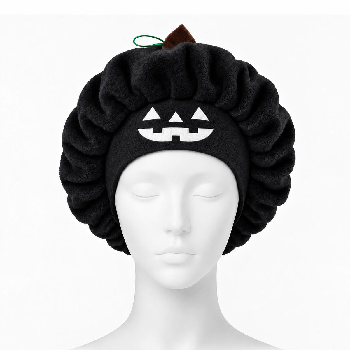 Black plush pumpkin sleep cap on a mannequin head with the jack-o'-lantern face at the front